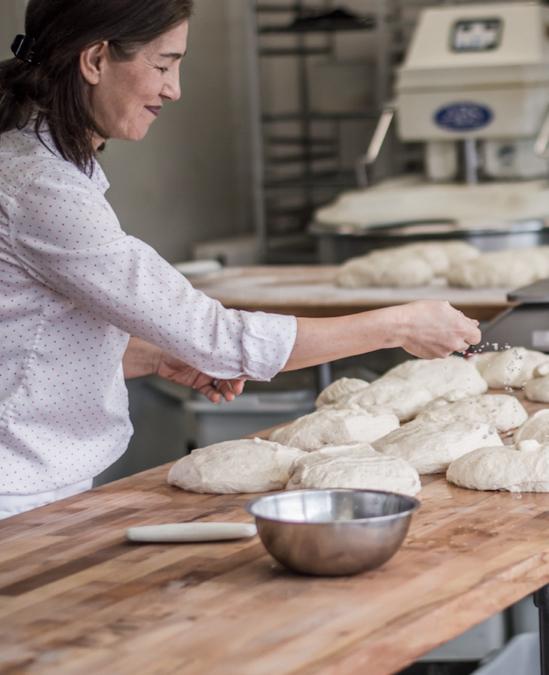 Dark-haired woman using dough to prepare a meal in her kitchen