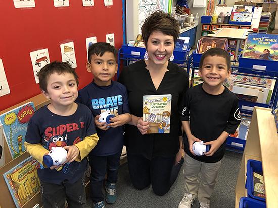 CSB employee with financial education book and 3 kids with piggy banks
