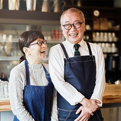 Business couple standing out front of shop smiling